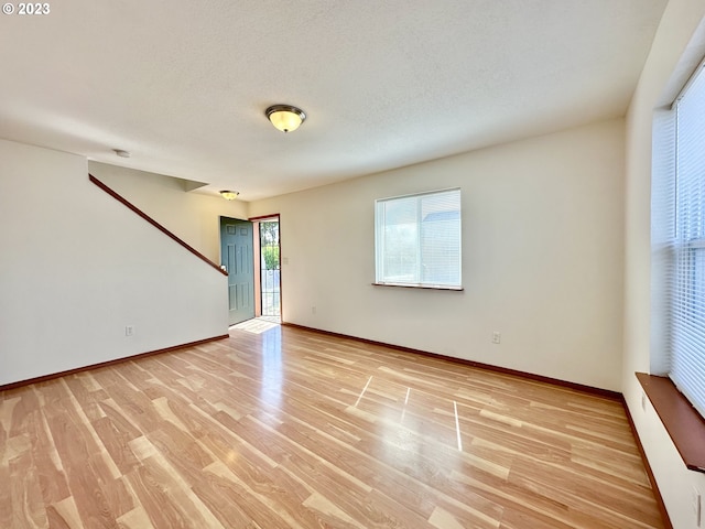 empty room featuring a textured ceiling and light hardwood / wood-style floors