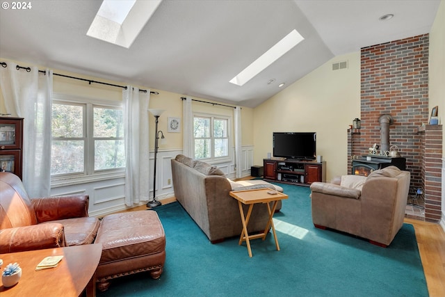 living room featuring hardwood / wood-style floors, a wood stove, and vaulted ceiling with skylight