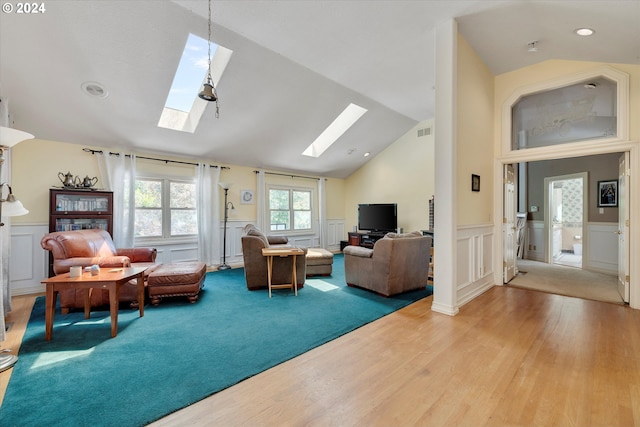 living room with light hardwood / wood-style floors and vaulted ceiling with skylight