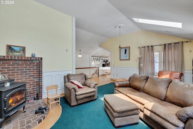 living room featuring wood-type flooring, lofted ceiling with skylight, and a wood stove