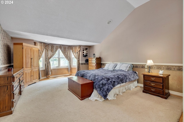 bedroom featuring vaulted ceiling, light colored carpet, and a textured ceiling