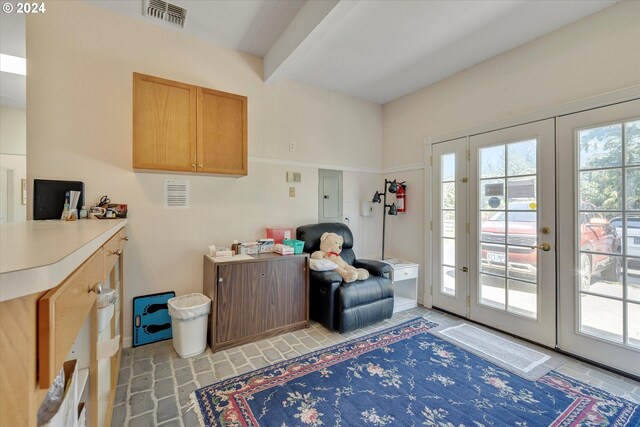 living area featuring beamed ceiling, plenty of natural light, electric panel, and french doors