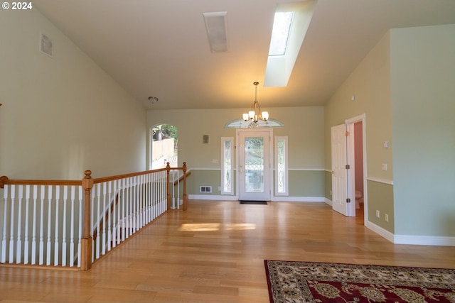 foyer entrance featuring a chandelier, light hardwood / wood-style floors, and lofted ceiling with skylight