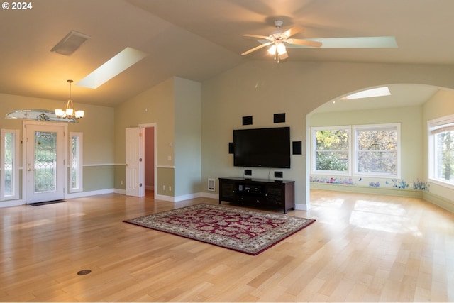 living room with ceiling fan with notable chandelier, light hardwood / wood-style floors, and high vaulted ceiling