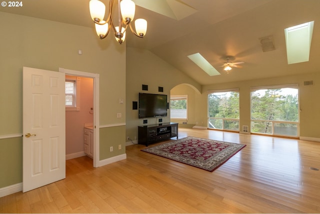 living room with ceiling fan with notable chandelier, a healthy amount of sunlight, light wood-type flooring, and high vaulted ceiling