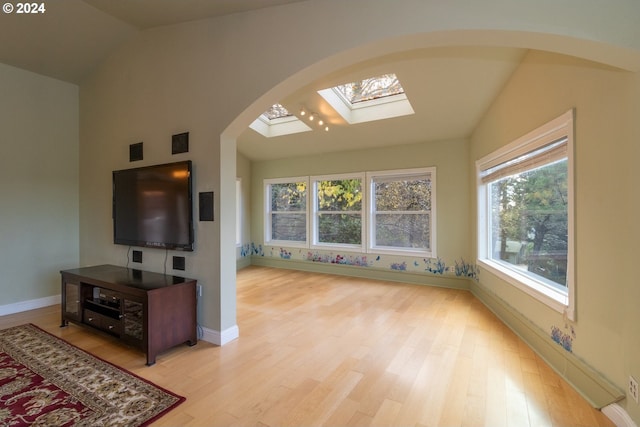 living room with light hardwood / wood-style floors, a healthy amount of sunlight, and lofted ceiling with skylight