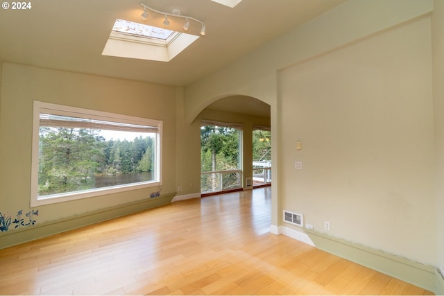 88378 Collard Lake Rd, Florence, OR 97439 - spare room with a skylight, arched walkways, light wood-style floors, and baseboards