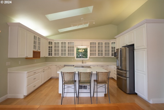 kitchen with white cabinets, light wood-type flooring, stainless steel refrigerator with ice dispenser, and a kitchen island