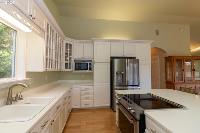 kitchen with light wood-type flooring, stainless steel appliances, white cabinetry, and sink