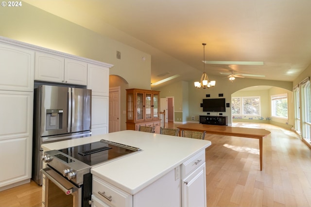 kitchen featuring ceiling fan with notable chandelier, stainless steel appliances, white cabinetry, and lofted ceiling