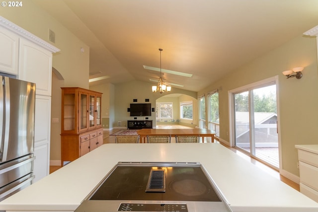 kitchen featuring stainless steel refrigerator, cooktop, pendant lighting, vaulted ceiling, and white cabinets