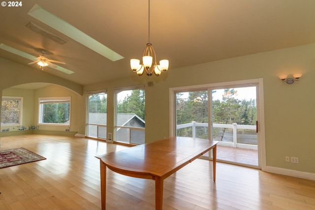 unfurnished dining area with ceiling fan with notable chandelier, light wood-type flooring, and a healthy amount of sunlight