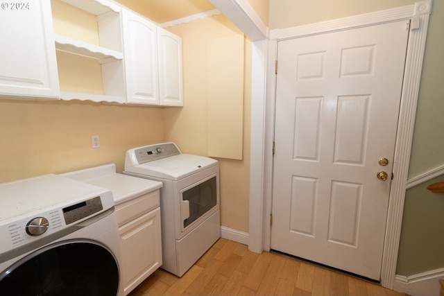 laundry room featuring cabinets, light wood-type flooring, and washing machine and dryer