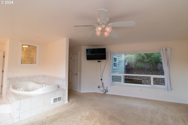 bathroom featuring ceiling fan and tiled tub