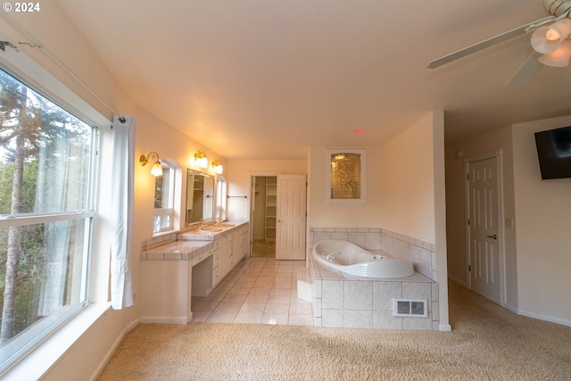 bathroom featuring tile patterned flooring, plenty of natural light, vanity, and tiled tub