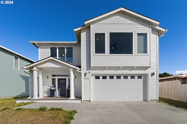 traditional-style home featuring covered porch, fence, driveway, and a garage