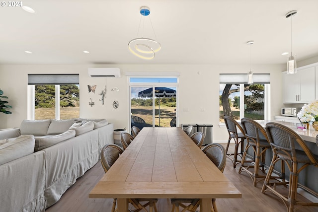dining area featuring plenty of natural light, a wall unit AC, and wood finished floors
