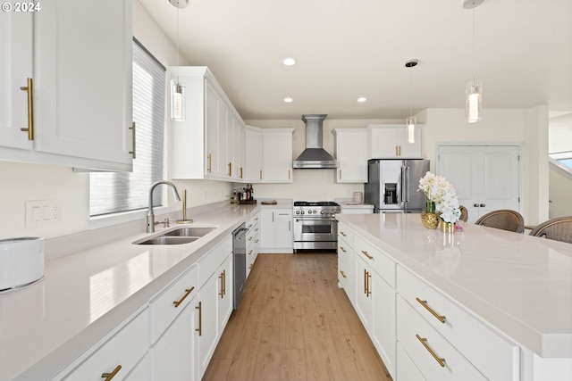 kitchen featuring wall chimney range hood, a center island, a sink, stainless steel appliances, and recessed lighting