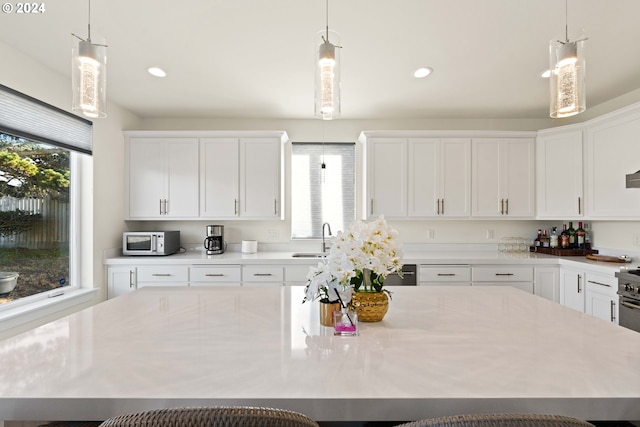 kitchen featuring a spacious island, hanging light fixtures, sink, and white cabinets
