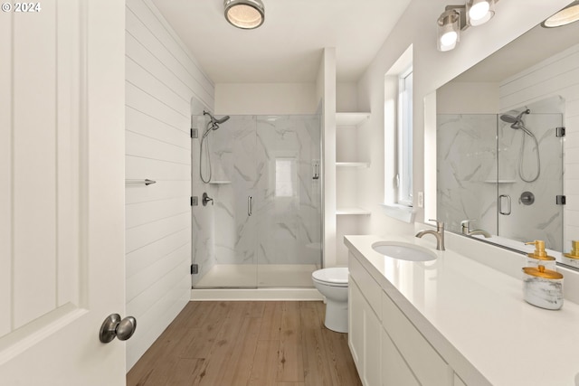 full bath with a marble finish shower, vanity, toilet, and wood finished floors