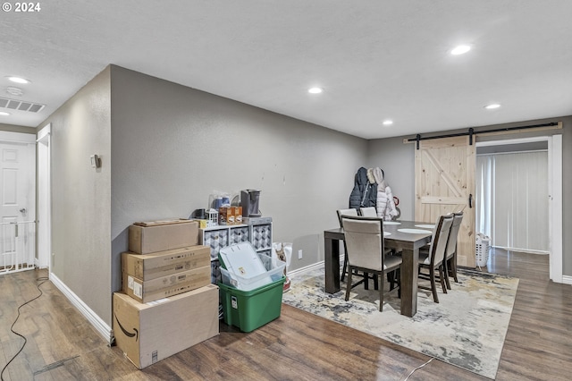 dining space with a barn door and hardwood / wood-style flooring