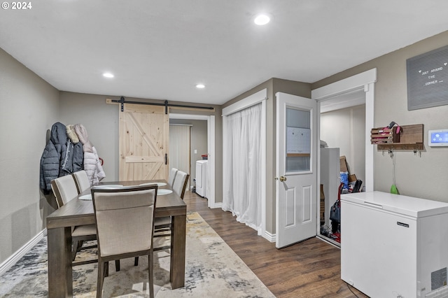 dining area with a barn door and dark hardwood / wood-style flooring