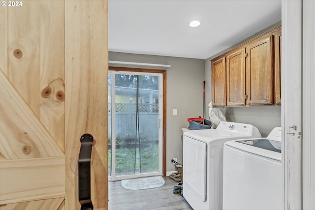 laundry area with washing machine and clothes dryer, light hardwood / wood-style flooring, and cabinets