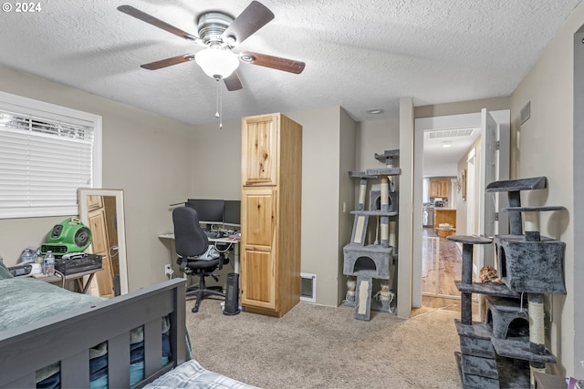 bedroom featuring light carpet, ceiling fan, and a textured ceiling