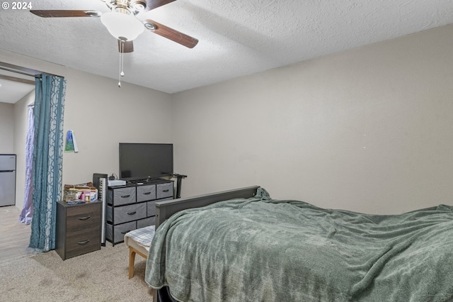 bedroom with ceiling fan, light colored carpet, and a textured ceiling