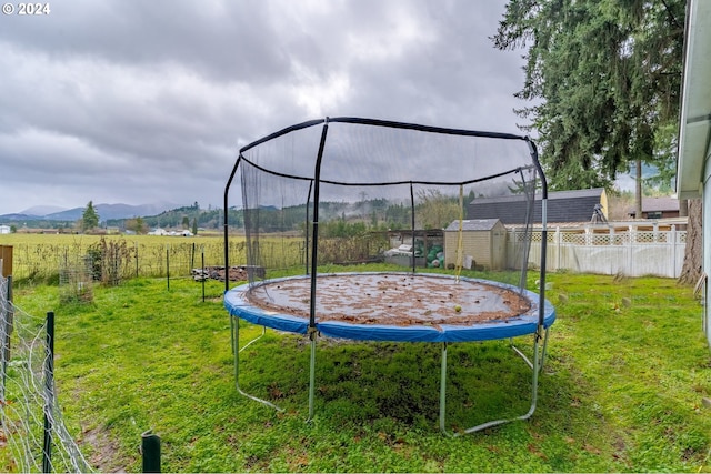 view of yard with a mountain view, a rural view, a trampoline, and a storage unit