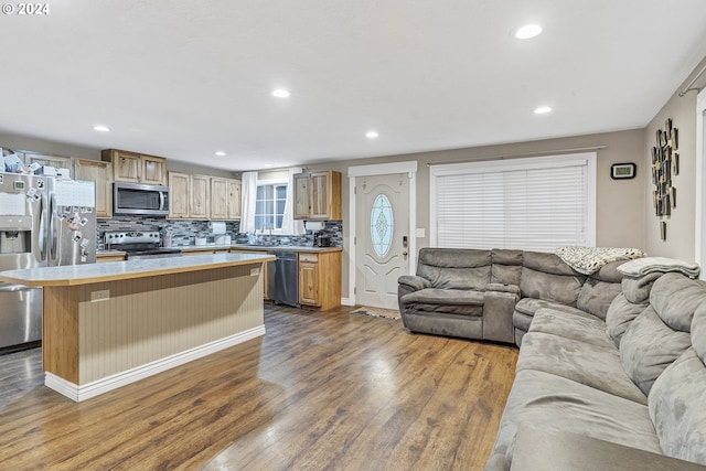 kitchen with tasteful backsplash, a kitchen breakfast bar, light hardwood / wood-style floors, a kitchen island, and appliances with stainless steel finishes