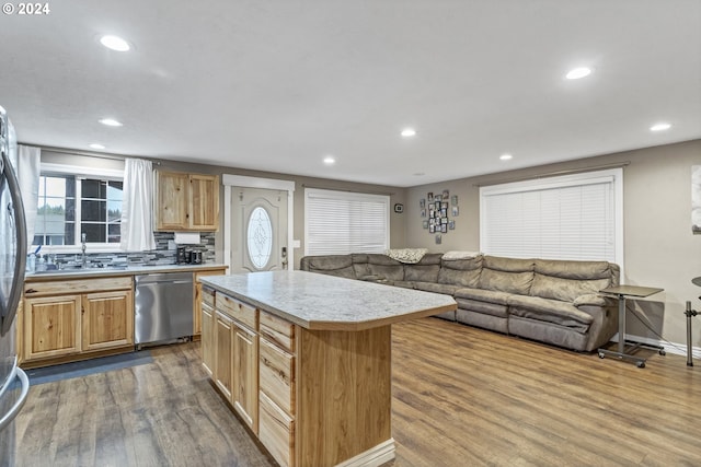 kitchen featuring dishwasher, backsplash, sink, light hardwood / wood-style floors, and a kitchen island