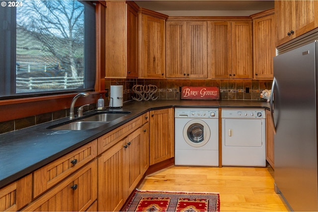 washroom with sink, cabinets, washing machine and clothes dryer, and light hardwood / wood-style floors