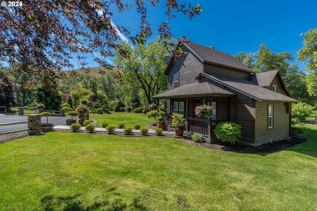 view of side of property featuring covered porch and a lawn