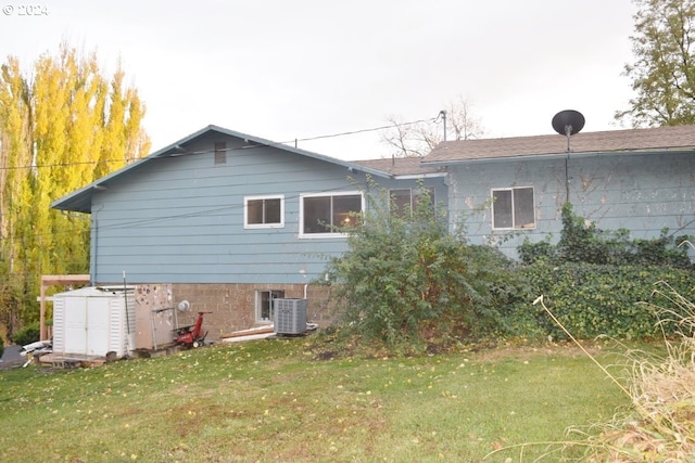 rear view of property with central air condition unit and a yard