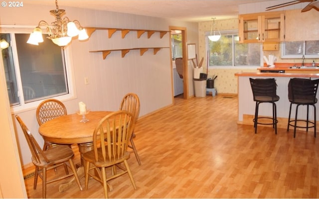 dining area with a chandelier, sink, and light hardwood / wood-style floors