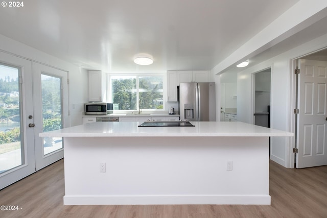 kitchen with appliances with stainless steel finishes, light wood-type flooring, a spacious island, and white cabinets