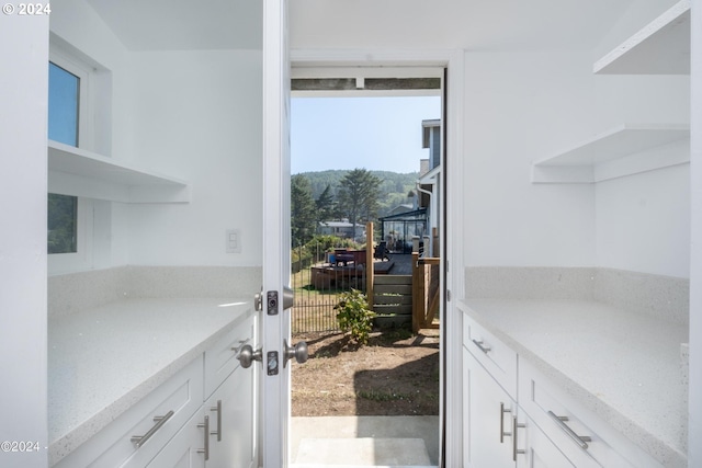 kitchen featuring light stone counters and white cabinetry