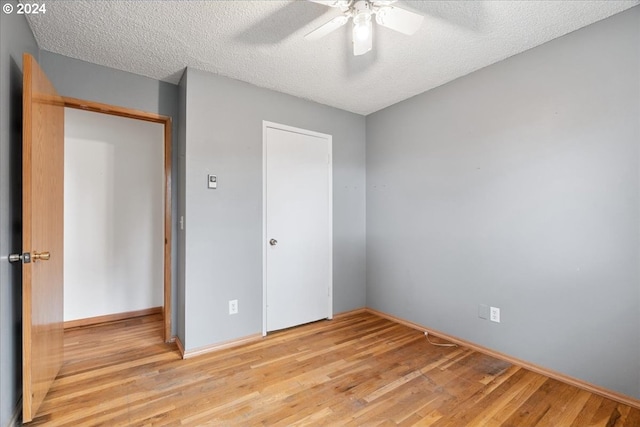 unfurnished bedroom featuring light wood-type flooring, a closet, ceiling fan, and a textured ceiling