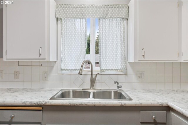 kitchen with white cabinets, backsplash, and sink