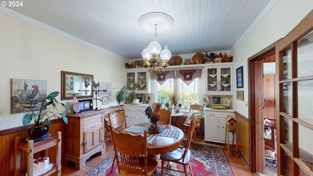 dining area with crown molding, an inviting chandelier, and light wood-type flooring