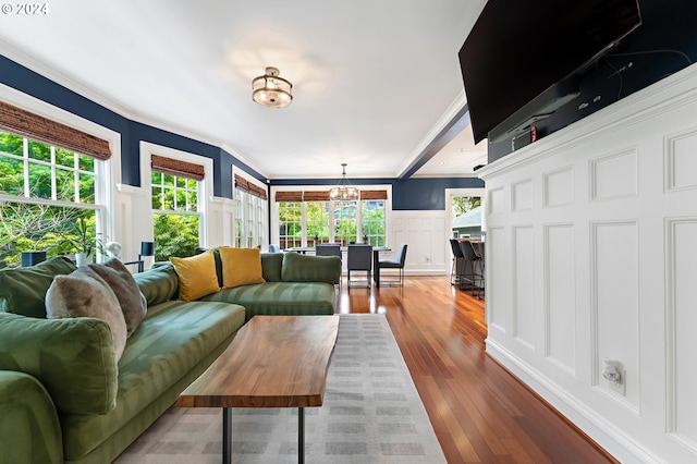 living room with hardwood / wood-style flooring, ornamental molding, and an inviting chandelier