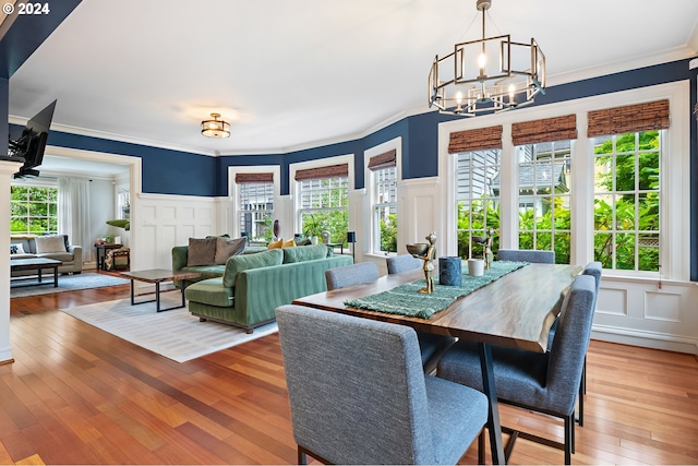 dining area with hardwood / wood-style flooring, a healthy amount of sunlight, and a notable chandelier