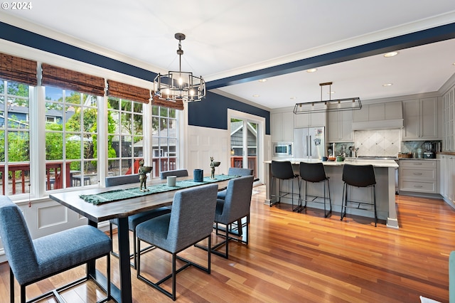 dining room with crown molding, plenty of natural light, a notable chandelier, and light wood-type flooring