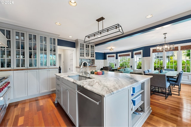 kitchen with dishwasher, sink, a kitchen island with sink, light hardwood / wood-style floors, and light stone countertops