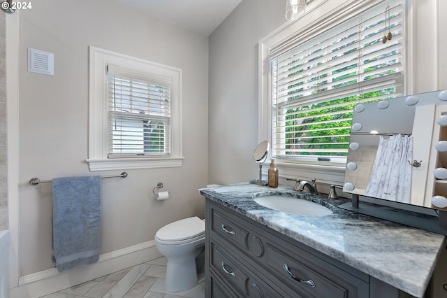 bathroom featuring vanity, a healthy amount of sunlight, and toilet