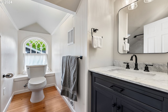 bathroom with hardwood / wood-style flooring, vanity, ornamental molding, vaulted ceiling, and toilet