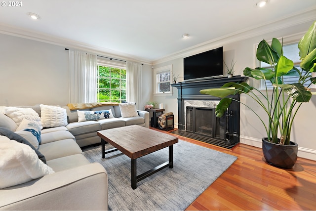 living room with a premium fireplace, ornamental molding, and light hardwood / wood-style flooring