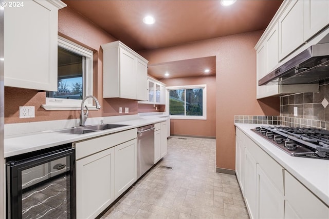 kitchen with white cabinetry, stainless steel appliances, sink, tasteful backsplash, and beverage cooler