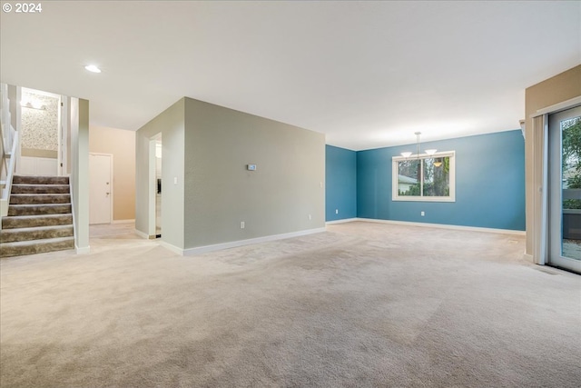 unfurnished living room featuring an inviting chandelier and light colored carpet